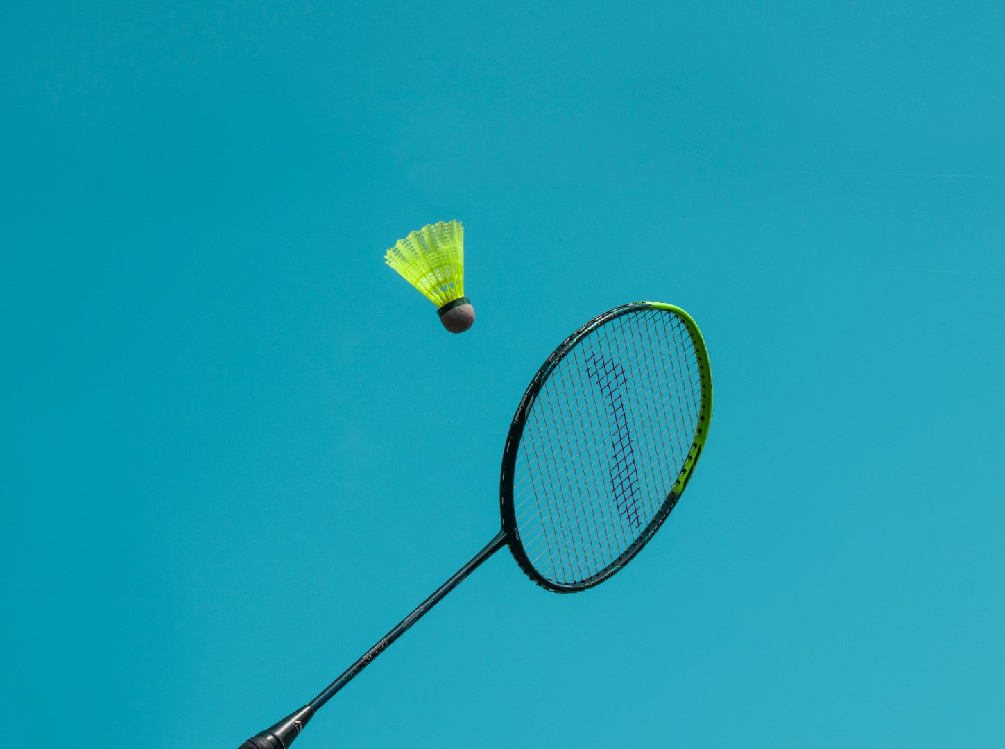 Badminton racket on blue background with yellow shuttlecock